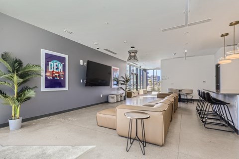 a living room with beige couches and a bar and a television